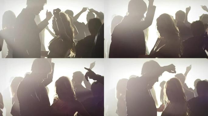 一群人在俱乐部跳舞的烟熏房间里的剪影