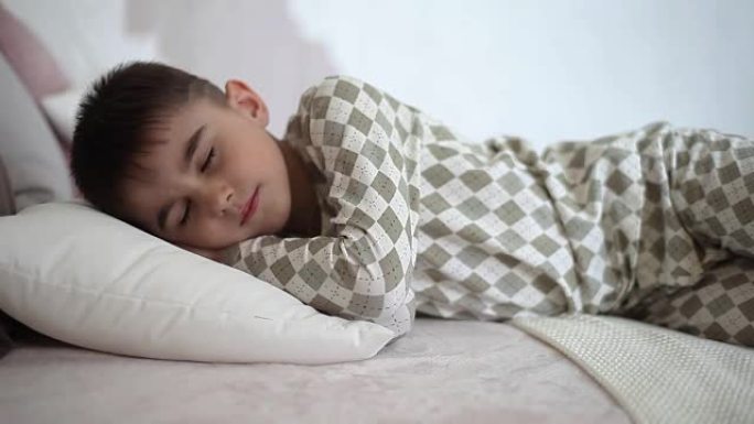 一个穿着睡衣的小男孩睡在床上