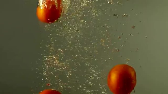 红色成熟的西红柿落在灰色背景下的水下。在红色史诗巨龙电影相机上拍摄。