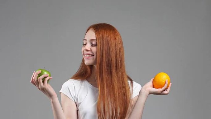 美丽的女孩在橙色或苹果之间选择