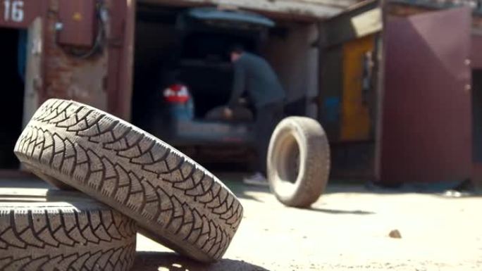 男子从车库的汽车后备箱中卸下轮胎