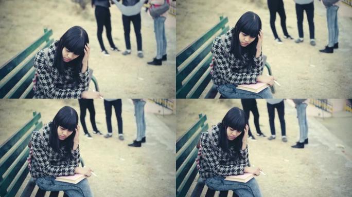 悲伤的大学生坐在长凳上，抱着她的头。
