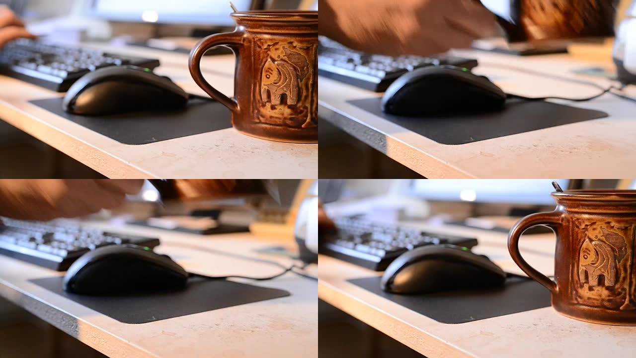男人在键盘上写字，喝茶。桌子被茶滴弄脏了。