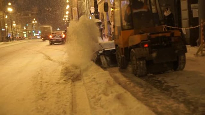 冬季大雪中夜间沿街道行驶的人和汽车