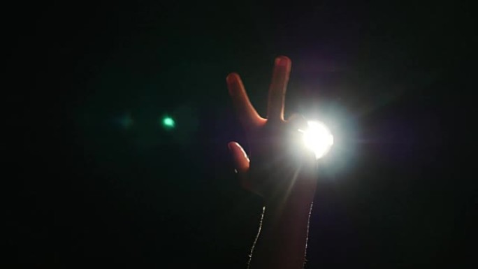 人类男性手的深色轮廓，在聚光灯下抬起手指或背光光，在黑色背景上带有手势，带有戏剧性的投影仪，光线或光