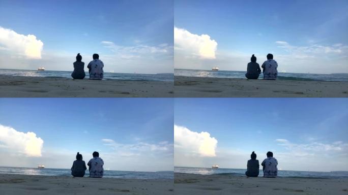 年轻浪漫的夫妇坐在海滩上欣赏美丽的景色