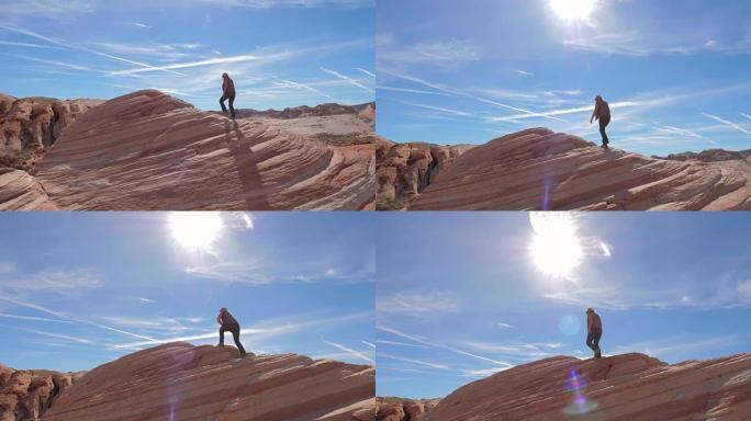运动徒步旅行女子爬上红色岩石背景天空慢动作4K
