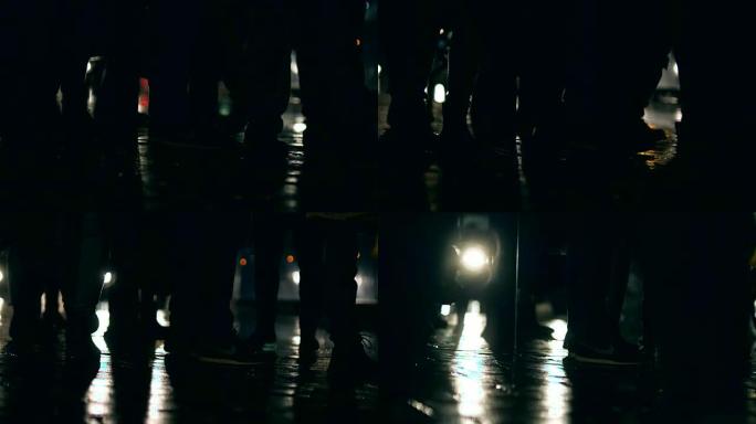 夜间下雨时人们在潮湿的人行道上行走的阴影