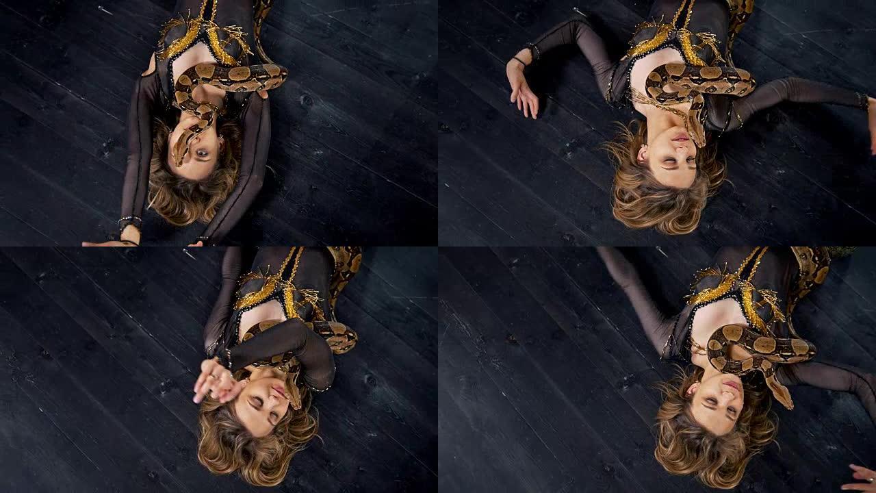 美丽的女人躺在地板上，蛇在工作室里跳舞