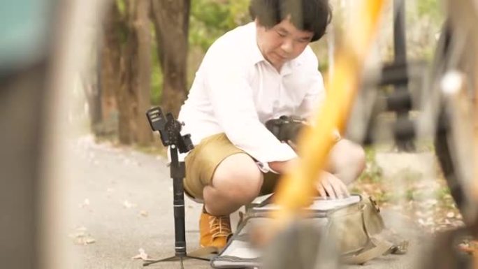 亚洲摄影师和电影制片人在回到公园之前将他的设备放在包里