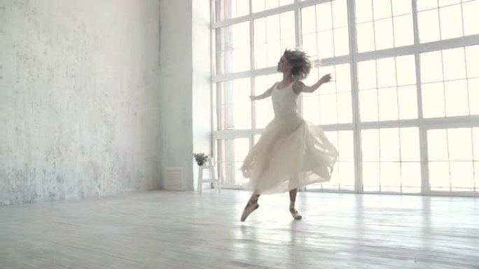 美丽的年轻芭蕾舞演员在一扇大窗户的背景上穿着轻便的飞行连衣裙跳舞。芭蕾舞演员tip着脚尖旋转，跳得很