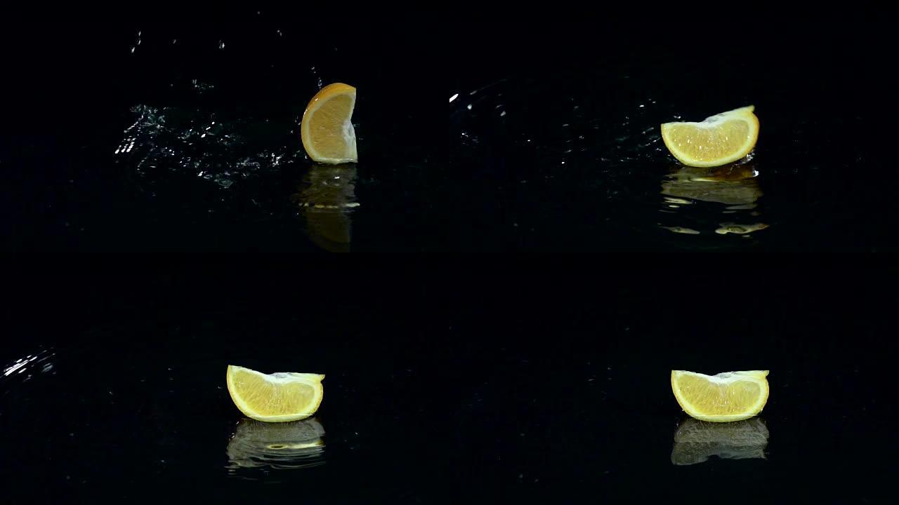 一片橙子掉入水中。黑色背景。慢动作