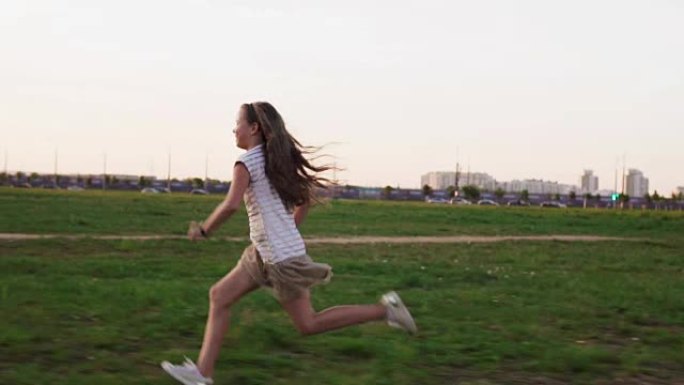 夏日快乐的小女孩在城市草坪上的草地上奔跑