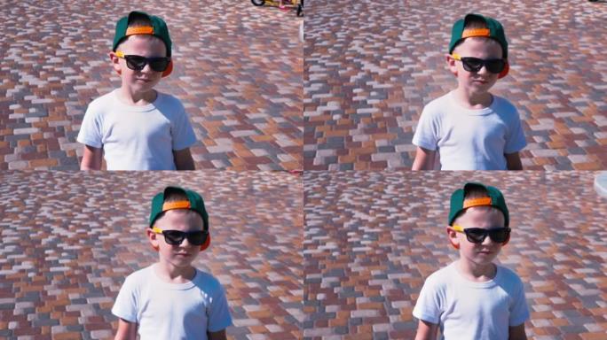 戴着墨镜和帽子的小男孩走在街上，孩子6岁的孩子走路，慢动作