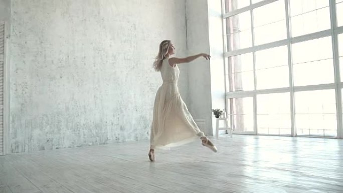 美丽的年轻芭蕾舞演员在大窗户背景上穿着轻便的飞行连衣裙跳舞