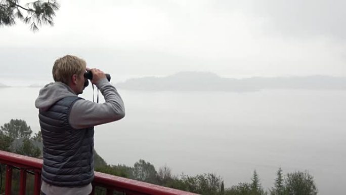 Man with Binoculars Looking Out Over Misty Panoram