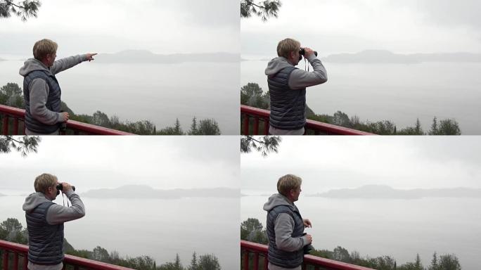 Man with Binoculars Looking Out Over Misty Panoram