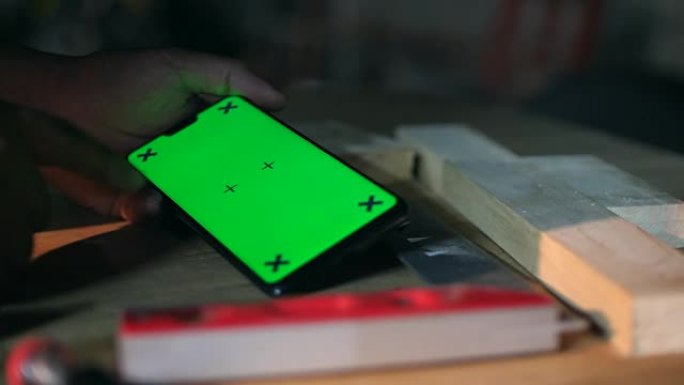 木匠在车间使用带绿屏的手机，色键