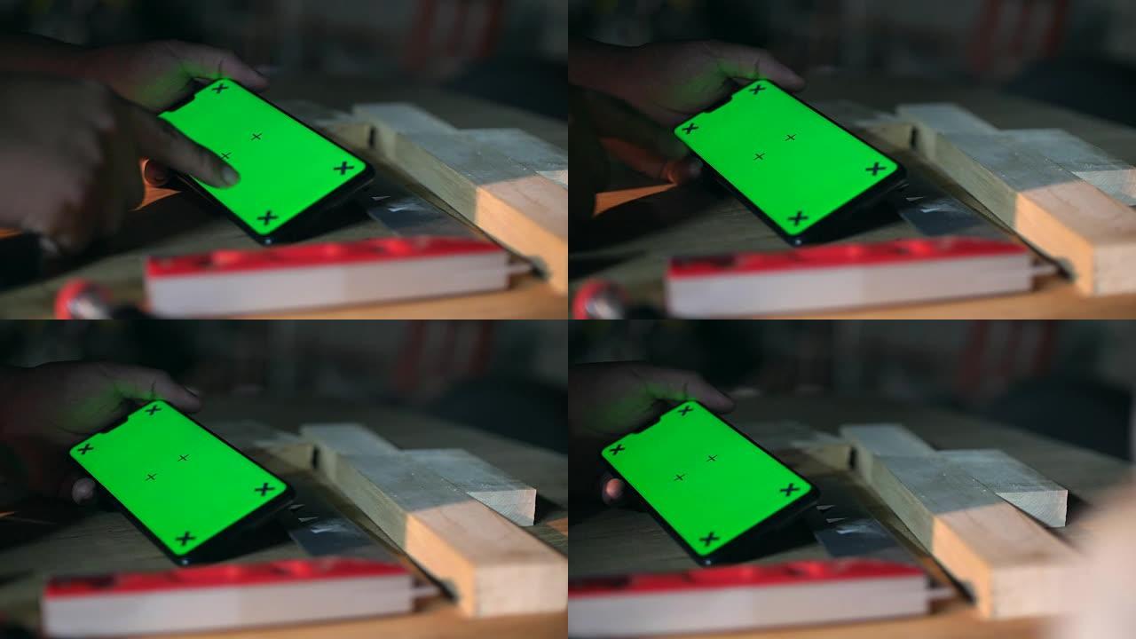 木匠在车间使用带绿屏的手机，色键