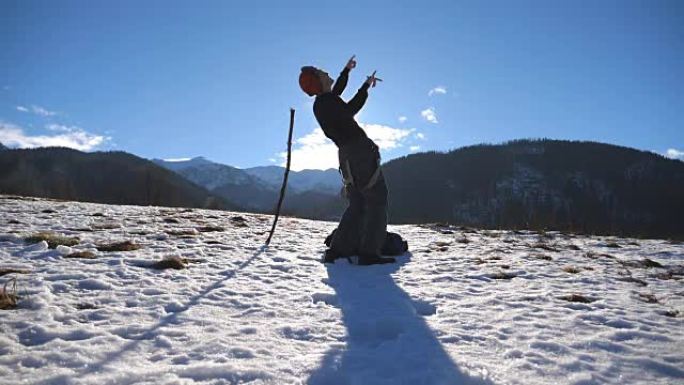 盖伊在白雪皑皑的风景背景下跳舞。男性游客在冬季大自然中玩耍。年轻快乐的人在冬季山区跳舞滑稽。慢动作特