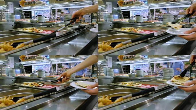 女人在自助餐厅将炸肉饼放在盘子上