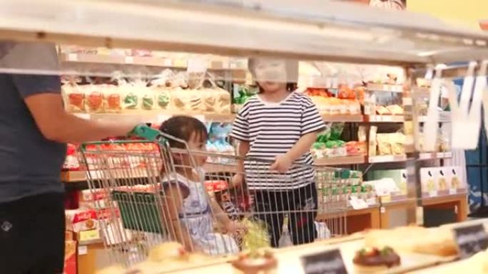 亚洲家庭由购物车上的男孩和女孩组成，父母在杂货店购物