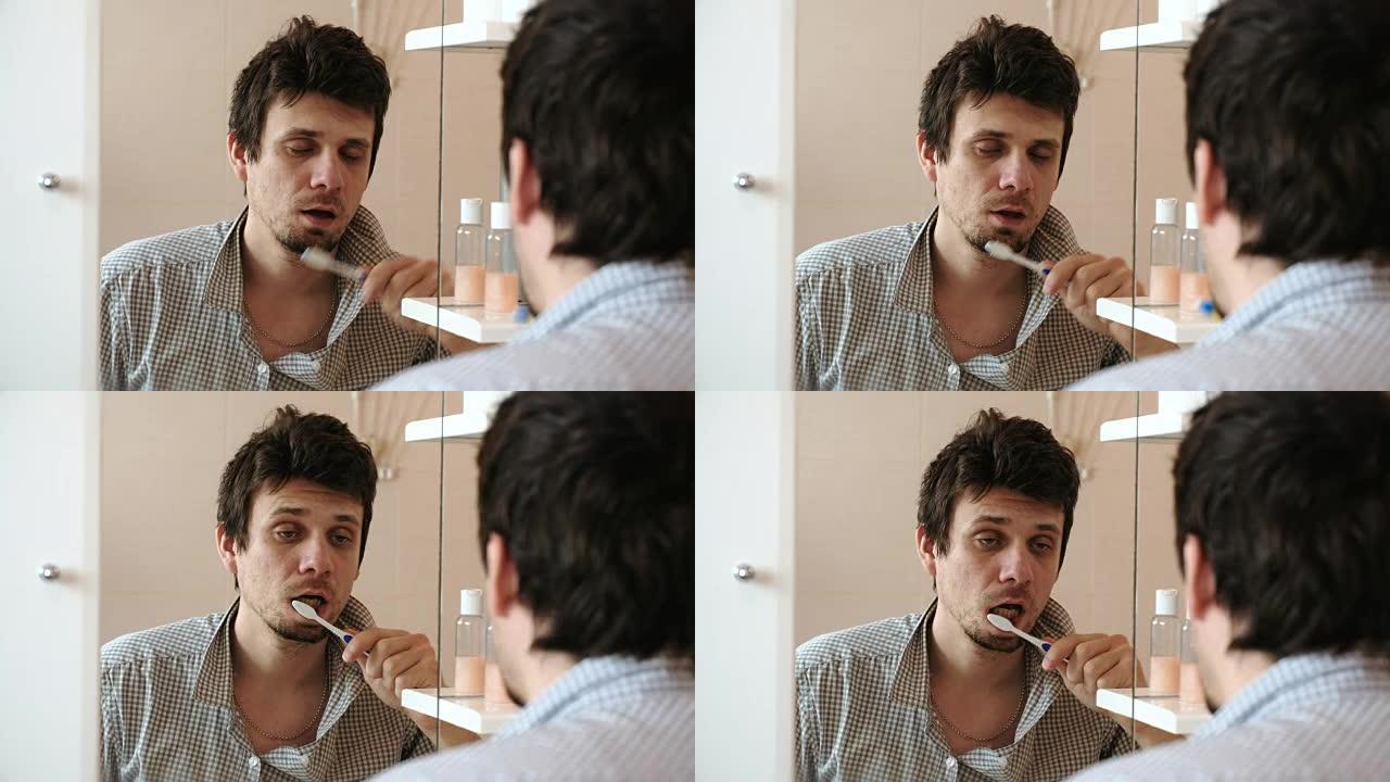 宿醉的疲倦困倦的人刚刚醒来，刷牙，看着镜子里的倒影。