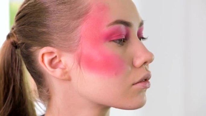 化妆师用化妆刷为年轻金发女人制作美丽的脸部艺术