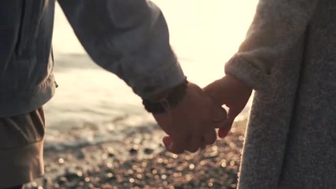 男人和女人的手的特写镜头，这对夫妇正站在海边