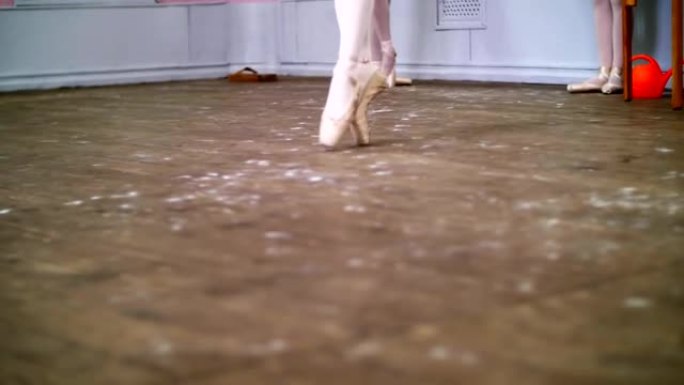 特写，在芭蕾舞课上，芭蕾舞演员在旧的木地板上表演了glissade en tournant，她优雅地