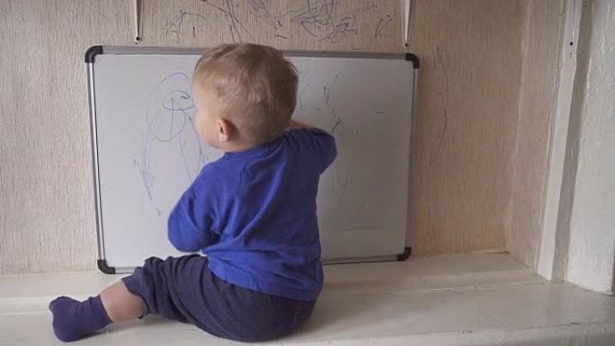 婴儿坐在窗台上，在标记板上画画。
