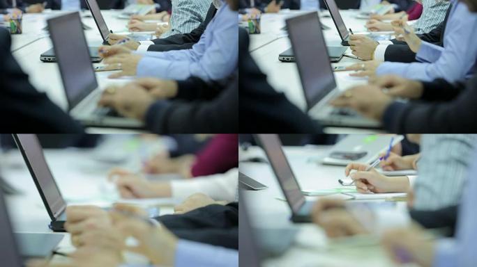 在现代办公室开会的商务人士的特写手。在会议室工作的人带着文件和电脑。