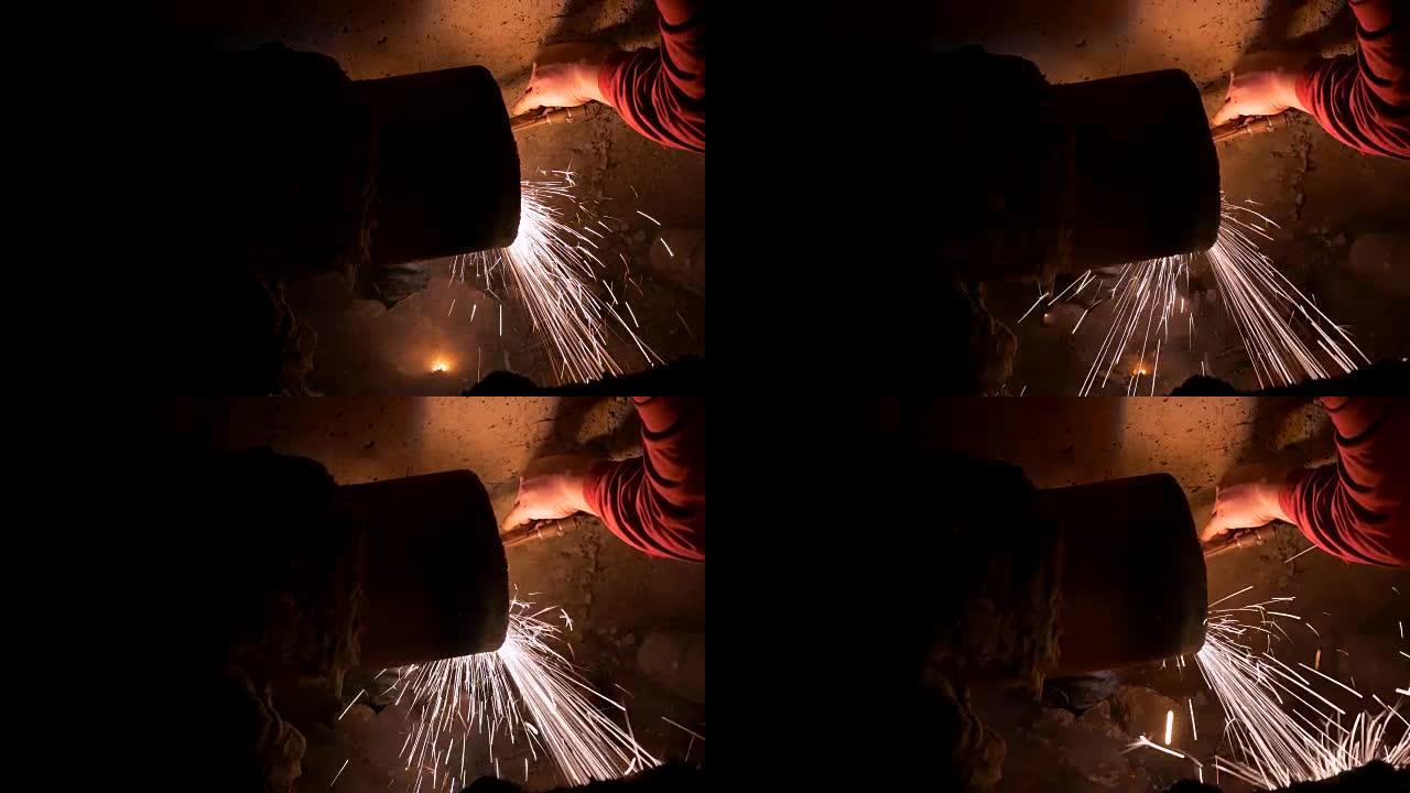 一名男子在夜间焊接加热系统管道的侧面镜头