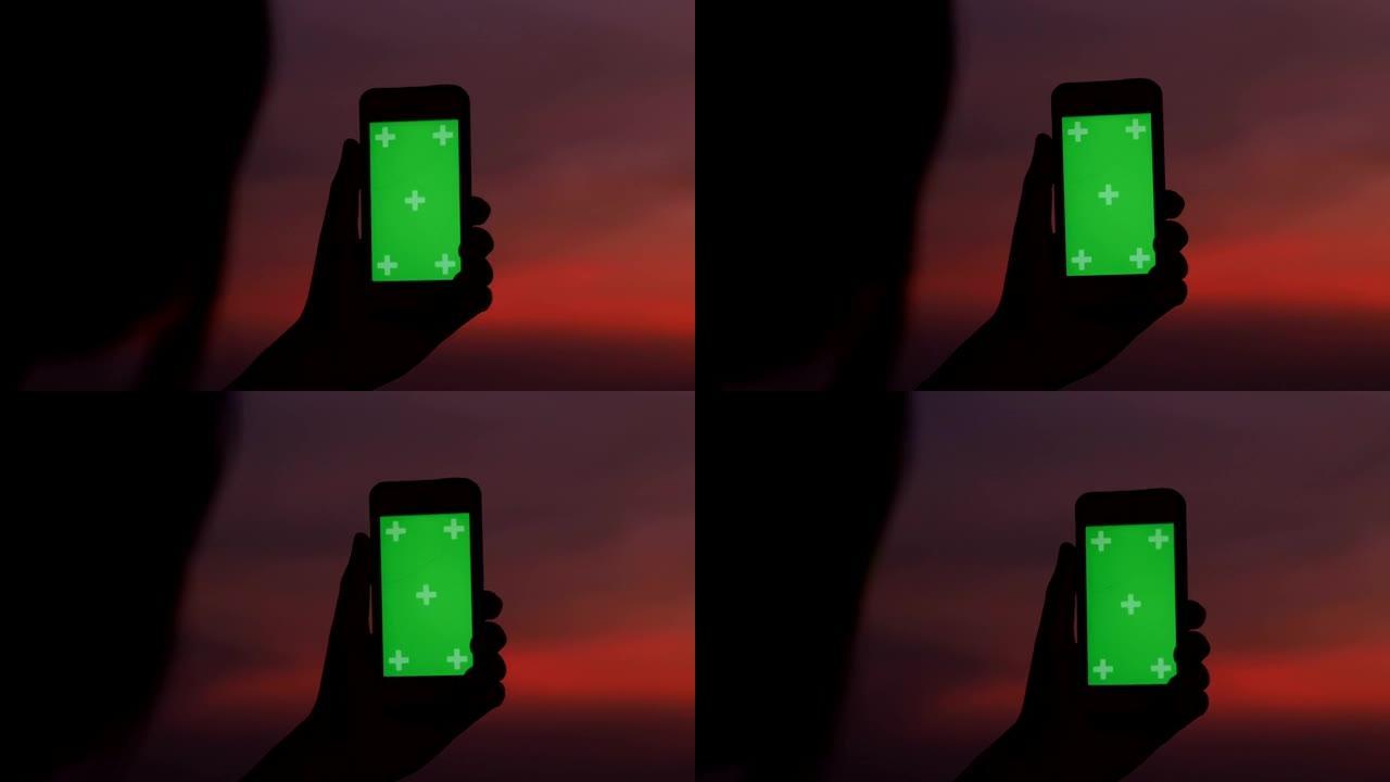 剪影女人的黄昏时间使用智能手机的色度键拍摄城市景观