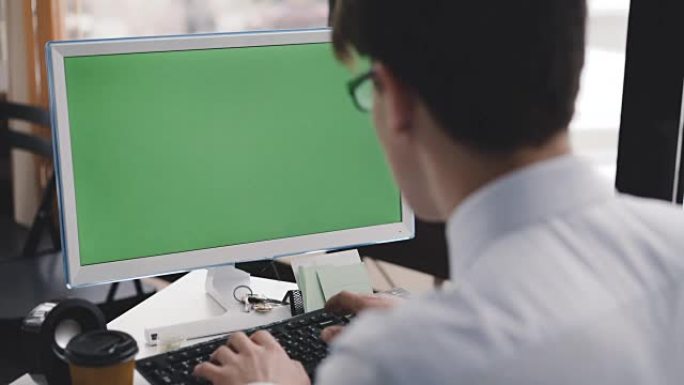 Young man works with pc with green screen and keyb