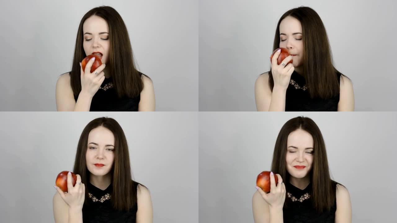 迷人的年轻女子吃了一个红苹果，微笑着
