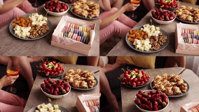 母鸡聚会的一些小吃的特写镜头。奢侈的生活方式。杏仁饼，卡纳普，木制茶几上的草莓