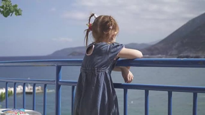 女孩站在酒店的阳台上，看着泻湖海