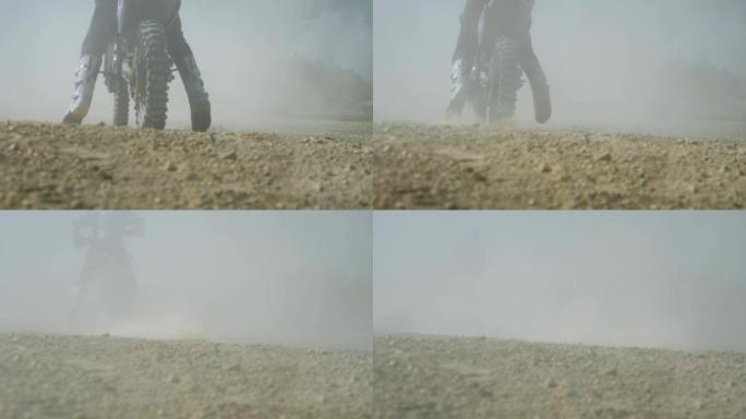 越野摩托车手骑着他的越野摩托车，扬起尘土。后视图慢动作低角度视图近