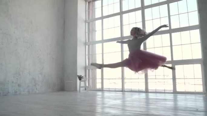 芭蕾舞演员穿着芭蕾舞短裙和脚尖鞋旋转并跳高。年轻的芭蕾舞演员在跳舞