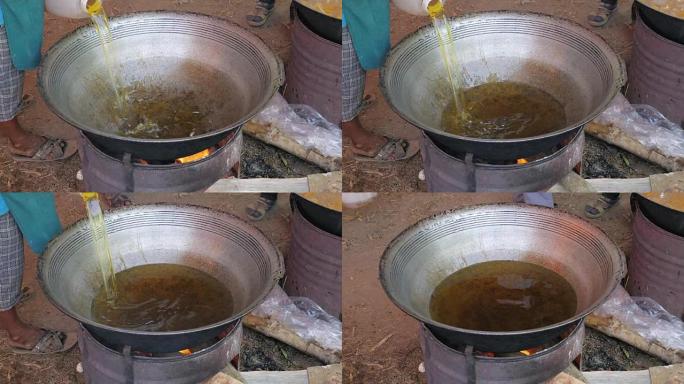 Woman pouring fried oil into a large outdoor wok c