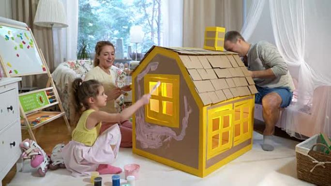 Young family with child building and painting toy 