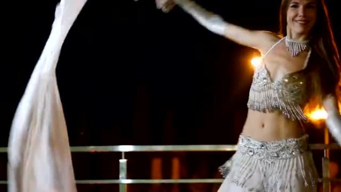 穿着东方民族服装的美丽年轻女子晚上在户外跳舞