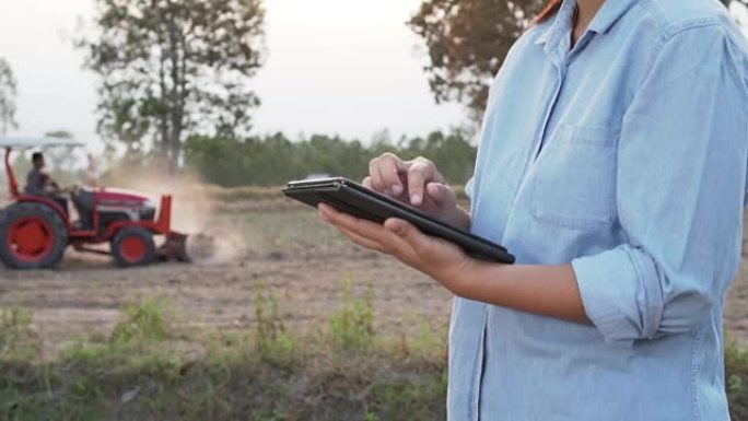 亚洲女性农民在农田使用便携式平板电脑。现代农耕理念，农业先进技术。