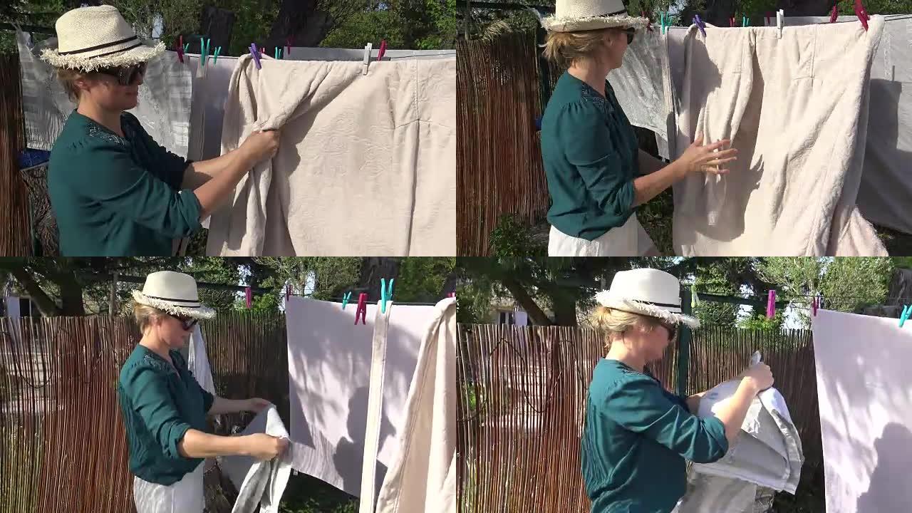 女人把湿衣服挂在晾衣绳上，在后院晾干
