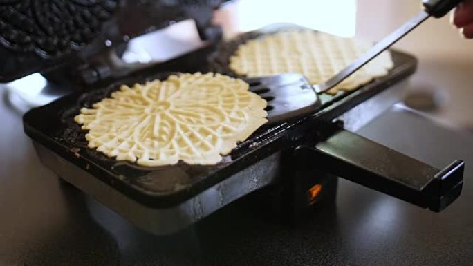 女人打开Pizzelle Maker移除两个Pizzelles