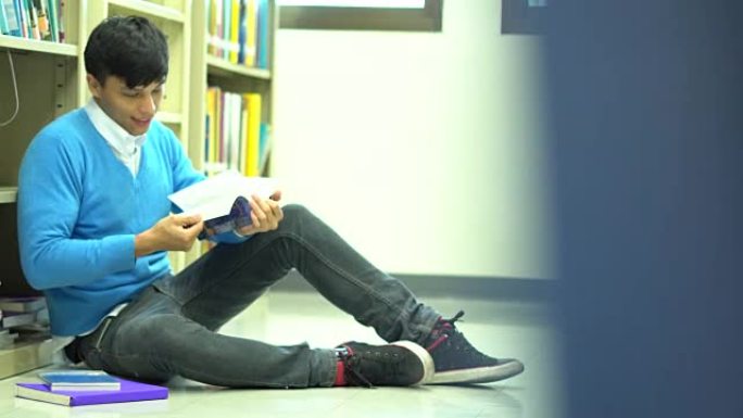 亚洲男子学生在学校图书馆看书