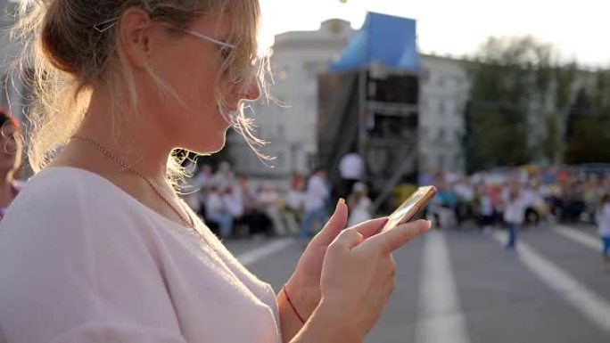 戴着太阳镜的快乐女性拿着安卓系统，站在市中心的移动互联网上