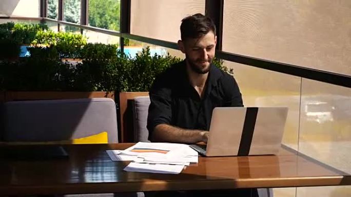 成功的工头在咖啡馆使用笔记本电脑和文档