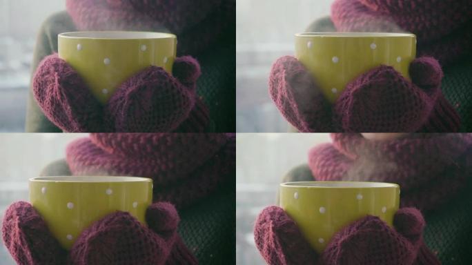 女人在冬天的早晨从黄色杯子里喝热茶或咖啡